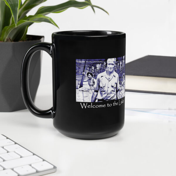 black glossy mug black 15 oz handle on left with image of the book cover for 'The History of Silver Lake as Told Through Its Deeds' showing an elderly man, Pappy, in foreground, two young women in a canoe behind him, and a young girl peeking from behind a tree saying ‘Welcome to the Lake’ on the historyofsilverlake.com website.