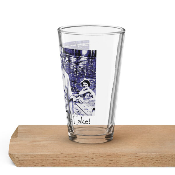 shaker pint glass 16 oz 16 oz left with image of the book cover for 'The History of Silver Lake as Told Through Its Deeds' showing, Pappy, in foreground from the "Great Book! No Cicadas!" billboard, two young women in a canoe behind him, and a young girl peeking from behind a tree saying ‘Welcome to the Lake’ on the historyofsilverlake.com website.