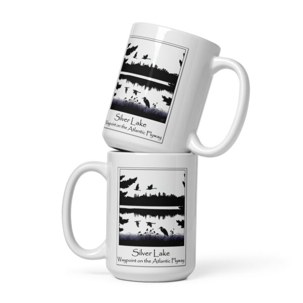 white glossy mug white 15 oz front view with an image of Silver Lake featuring a blue heron in the foreground and Canada Geese in flight overhead, highlighting Silver Lake as a waypoint on the American Atlantic Flyway from the book "The History of Silver Lake as Told Through Its Deeds".